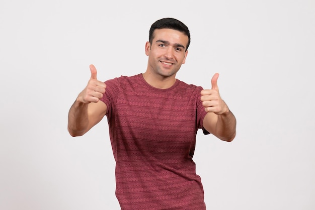 Jovem do sexo masculino com uma camiseta vermelho-escura em pé sobre um fundo branco de frente
