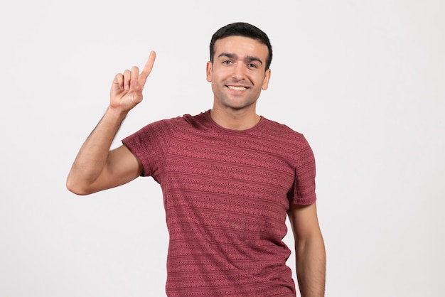 Jovem do sexo masculino com uma camiseta vermelho-escura em pé sobre um fundo branco de frente