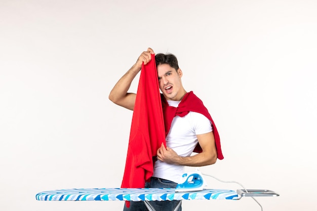 Jovem do sexo masculino, de frente, dobrando a toalha vermelha no branco