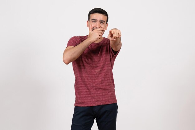 Jovem do sexo masculino de frente para a camiseta, posando e rindo no fundo branco