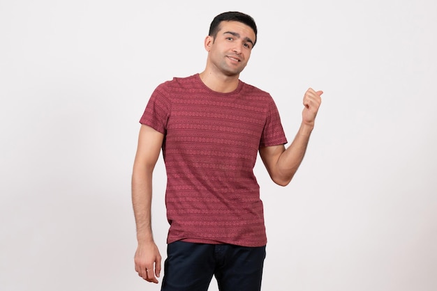 Jovem do sexo masculino de frente para a camiseta, posando e sorrindo no fundo branco