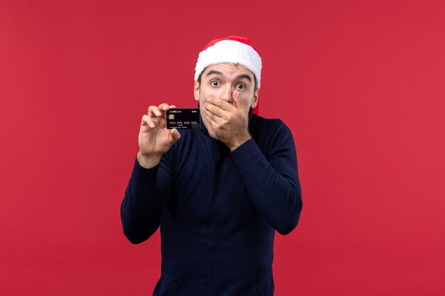 Jovem do sexo masculino segurando um cartão preto sobre o fundo vermelho