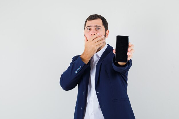 Jovem do sexo masculino segurando um celular na camisa