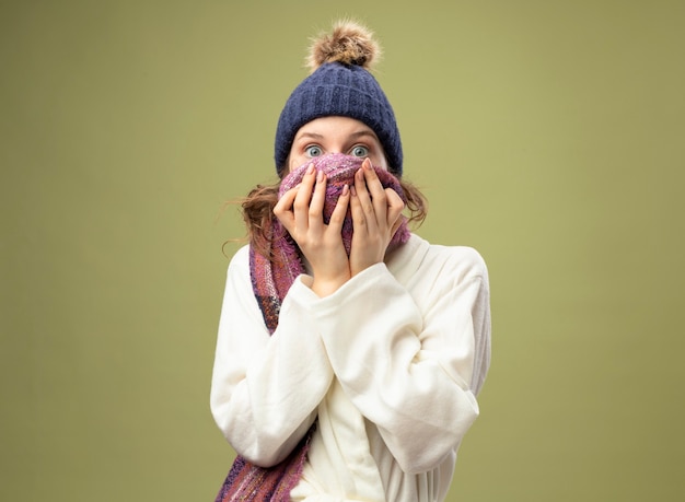 Foto grátis jovem doente com medo usando túnica branca e chapéu de inverno com lenço coberto com lenço no rosto