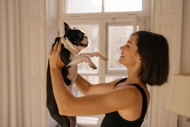 Foto grátis jovem dona caucasiana brincando com alegre cachorro preto e branco em casa brinque com o conceito de animal de estimação