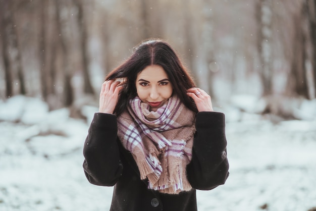 Jovem e bela modelo posando na floresta de inverno