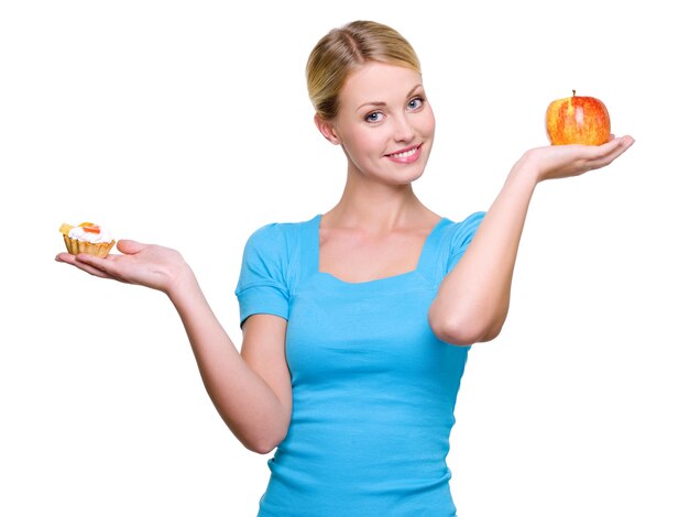 Jovem e bela mulher escolher entre bolo doce e maçã vermelha