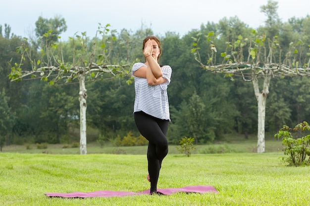 Jovem e bela mulher fazendo exercícios de ioga ao ar livre