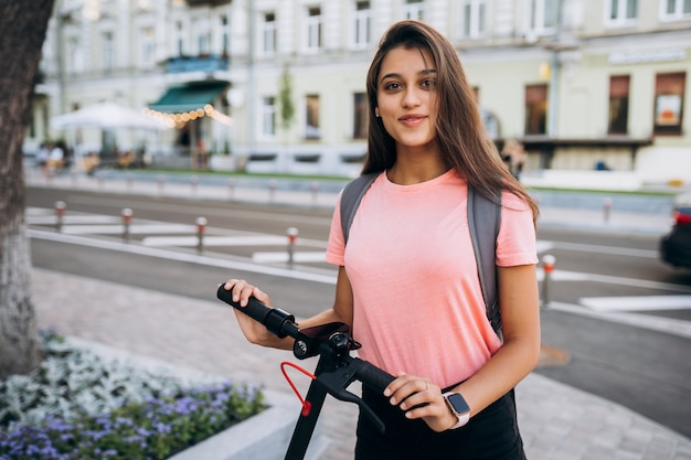 Jovem e bela mulher montando uma scooter elétrica.