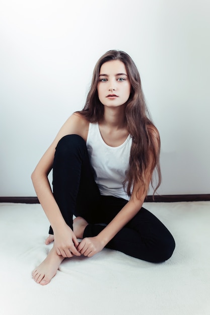 Jovem e bela mulher posando em uma parede branca