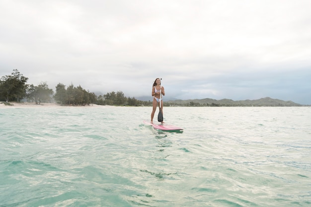 Jovem e bela mulher surfando no Havaí