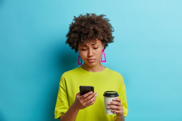 Jovem e bonita afro-americana descontente olhando com tristeza para o smartphone