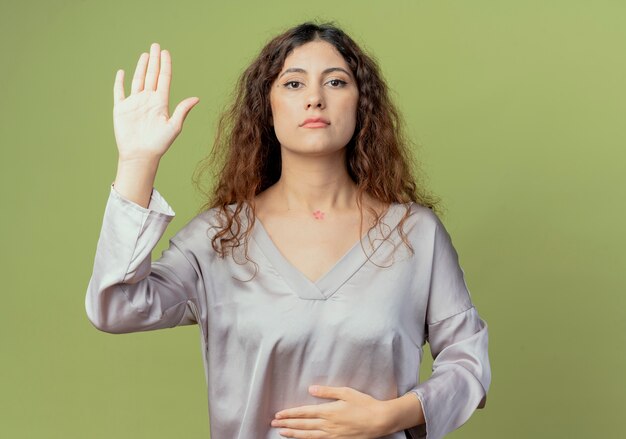 jovem e bonita trabalhadora de escritório colocando a mão na barriga e mostrando um gesto de parada isolado na parede verde oliva
