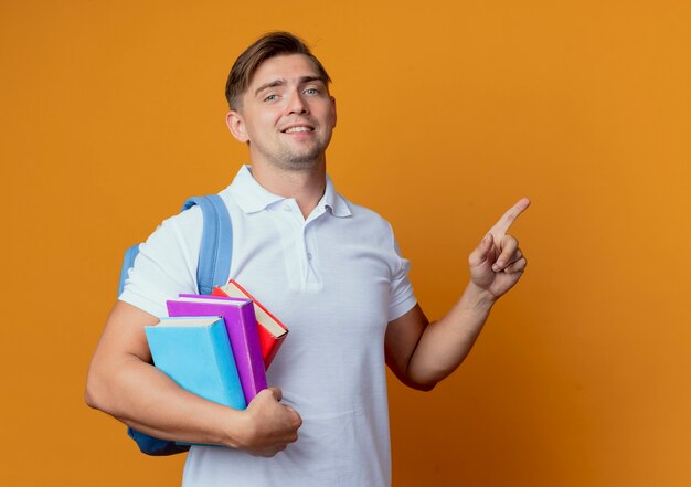 Jovem e bonito estudante do sexo masculino com uma bolsa nas costas segurando livros