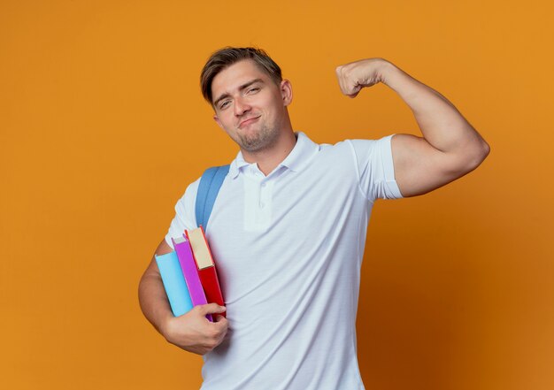 Jovem e bonito estudante do sexo masculino com uma bolsa nas costas segurando livros