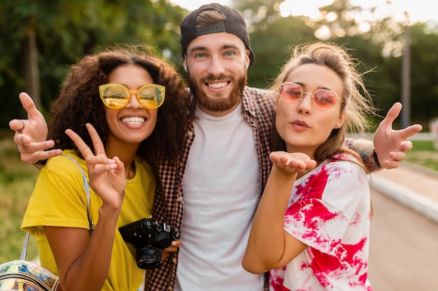 Jovem e feliz companhia de amigos sorridentes e emocionais caminhando no parque com a câmera fotográfica, homens e mulheres se divertindo juntos