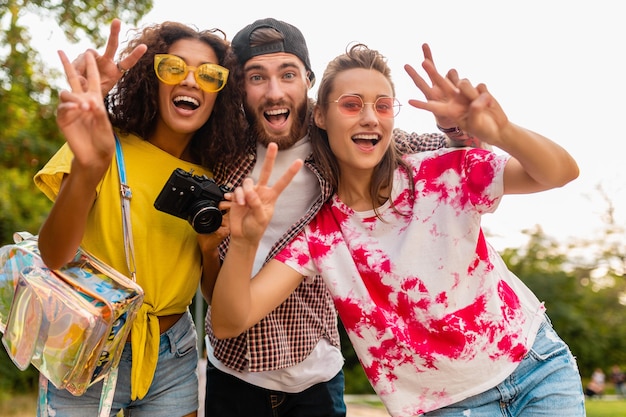 Foto grátis jovem e feliz companhia de amigos sorridentes e emocionais caminhando no parque com a câmera fotográfica, homens e mulheres se divertindo juntos