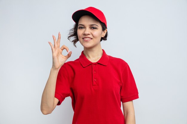 Jovem e linda entregadora sorridente gesticulando sinal de ok