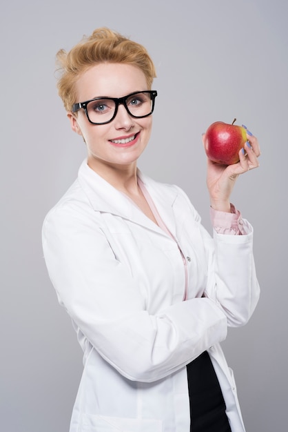 Foto grátis jovem e linda médica segurando uma maçã madura