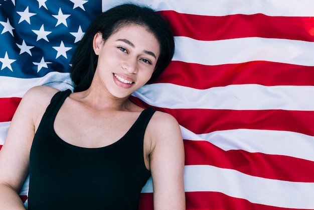 Jovem e linda mulher deitada na bandeira americana