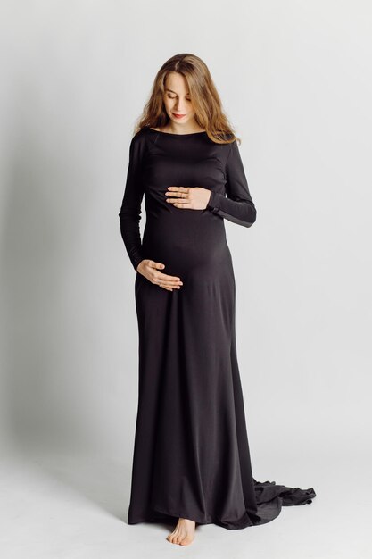 Jovem e linda mulher grávida de vestido preto Conceito de aparência de moda de gravidez