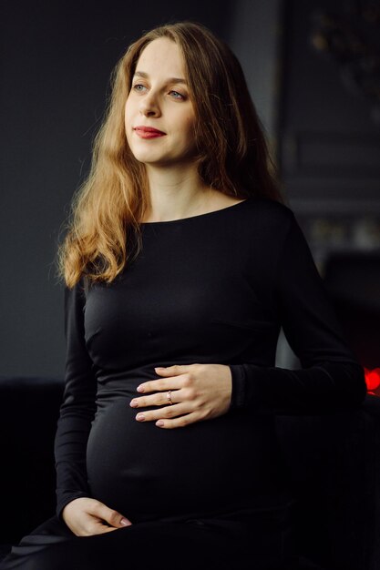 Jovem e linda mulher grávida de vestido preto Conceito de aparência de moda de gravidez