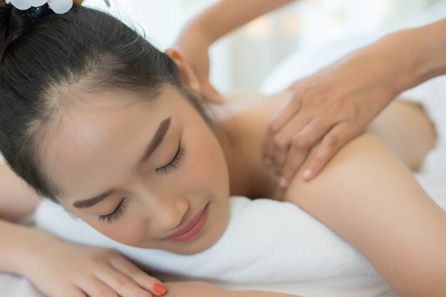 Jovem e linda mulher relaxante durante a massagem no salão de spa.