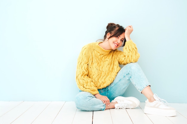 Jovem e linda mulher sorridente em jeans e suéter amarelo moderno de verão