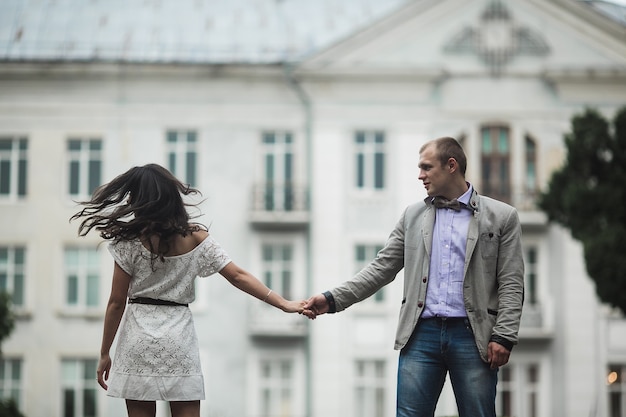 Jovem e lindo casal europeu se divertindo no fundo da cidade