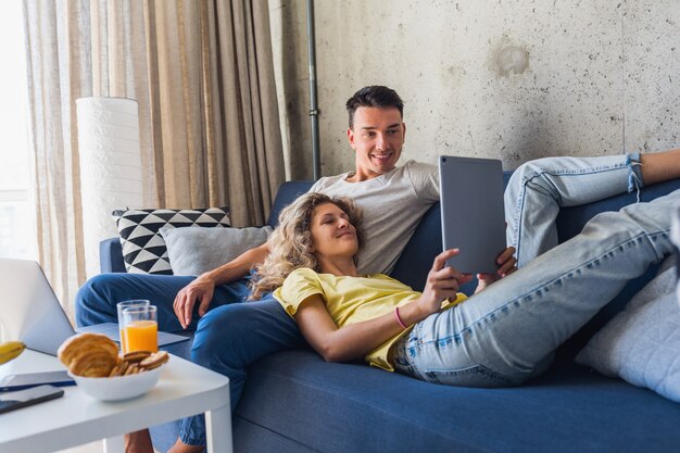 Jovem e mulher apaixonados sentados em casa trabalhando online