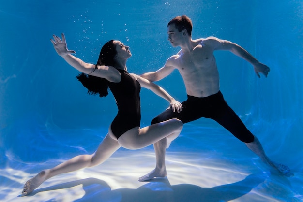 Jovem e mulher posando juntos submersos