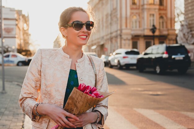 Jovem elegante e linda mulher caminhando na rua ao pôr do sol