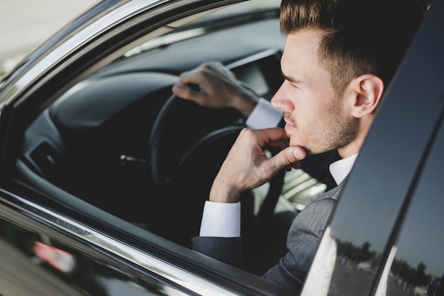 Jovem elegante pensativo sentado no carro