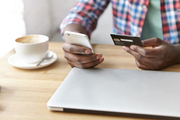 Foto grátis jovem elegante sentado em um café com smartphone e laptop