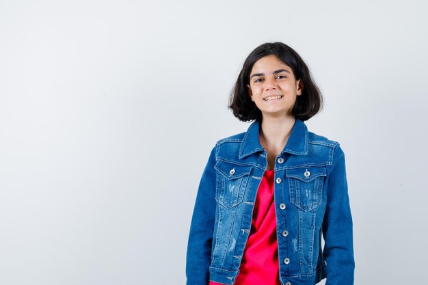 Jovem em linha reta e posando para a câmera em t-shirt vermelha e jaqueta jeans e parece feliz.