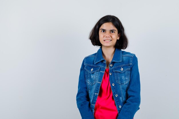 Jovem em linha reta e posando para a câmera em t-shirt vermelha e jaqueta jeans e parece feliz.