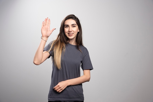 Jovem em pé e posando com a mão levantada