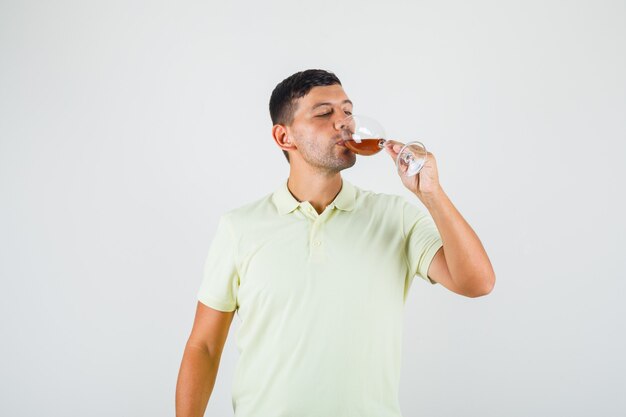 Jovem em t-shirt bebendo um copo de álcool.