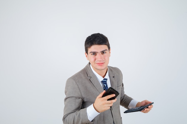 Jovem em terno formal segurando um telefone e uma calculadora