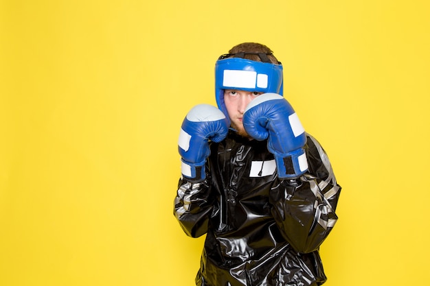 Jovem em traje esporte preto e luvas de boxe azuis