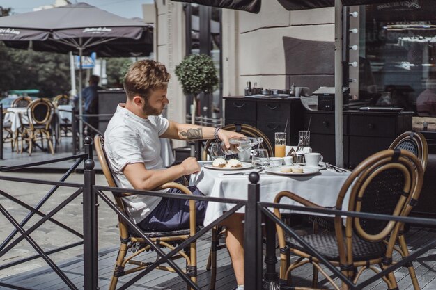 jovem em um café de verão no terraço toma café da manhã