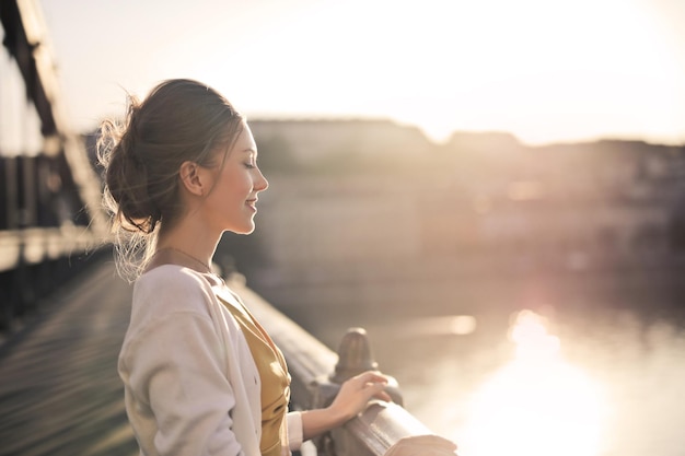 Foto grátis jovem em uma ponte em frente a um pôr do sol