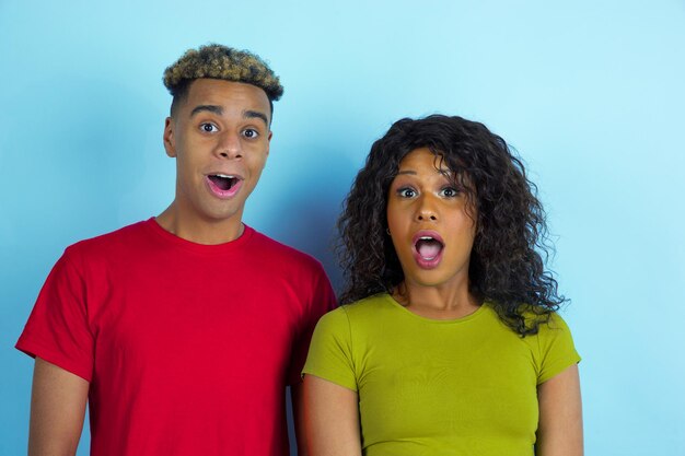 Jovem emocional afro-americano e mulher em fundo azul