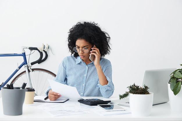 Jovem empreendedora séria e concentrada falando no celular