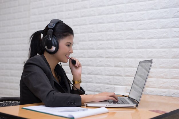 Jovem empresária com fone de ouvido sentado na mesa do escritório