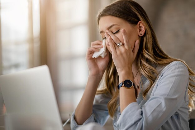 Jovem empresária com vírus de resfriado e gripe com dor de cabeça enquanto trabalhava no escritório