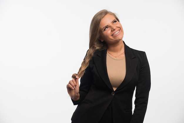 Foto grátis jovem empresária em um terno preto parece feliz e sorridente.