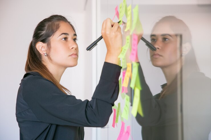 Foto grátis jovem empresária latina escrevendo na etiqueta com marcador. focada gerente feminina linda morena confiante, compartilhando a ideia para o projeto e fazendo anotações. brainstorming, negócios e conceito de treinamento