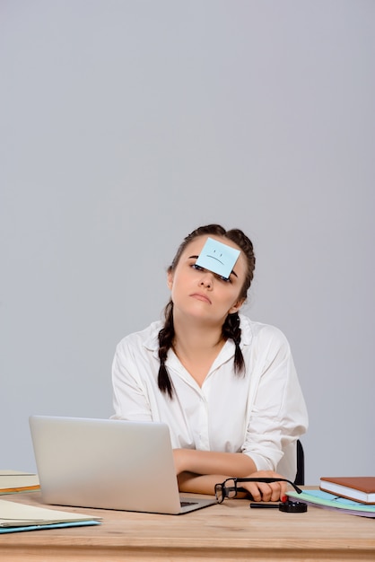 Foto grátis jovem empresária linda sentada com adesivo na testa no local de trabalho