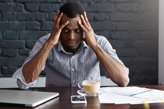 Foto grátis jovem empresário afro-americano frustrado com forte dor de cabeça